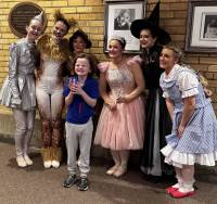 Cast of Wizard of Oz standing behind a young child with sensory needs