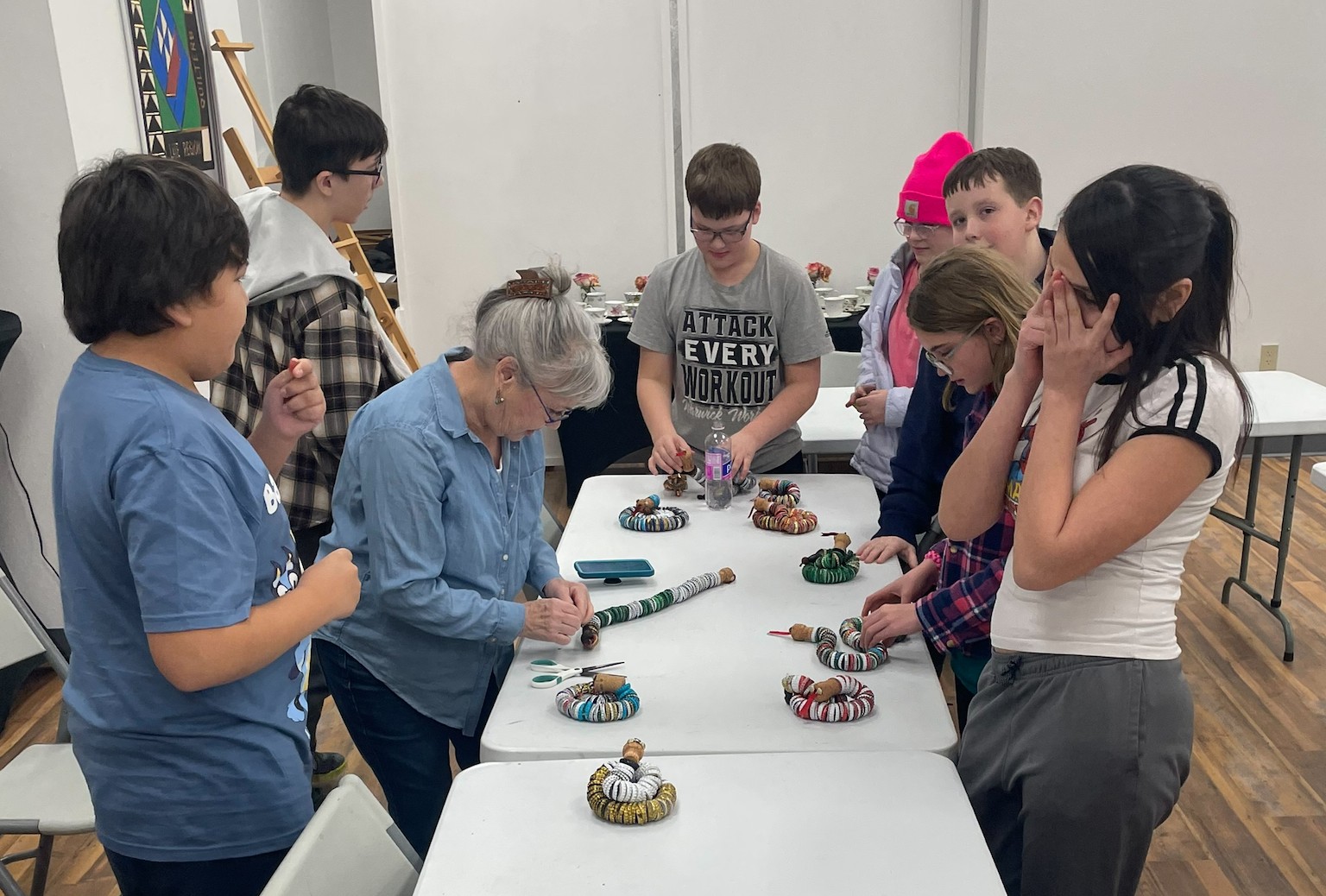teaching artist shows seven middle-school students how to make snakes from bottle caps 