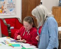 a teaching artist is observing a Devil's Lake middle school student as she created art at a table with supplies all around