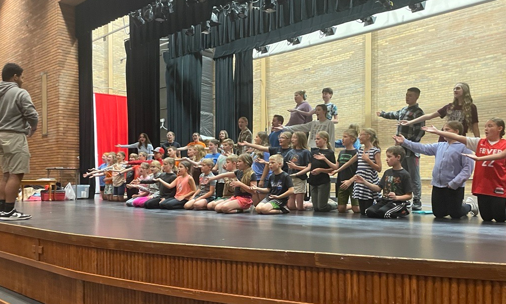 Dickinson Catholic Schools students on a stage, working on the Alice in Wonderland production with Missoula Children's Theatre with funds from NDCA's Artist in Residence program