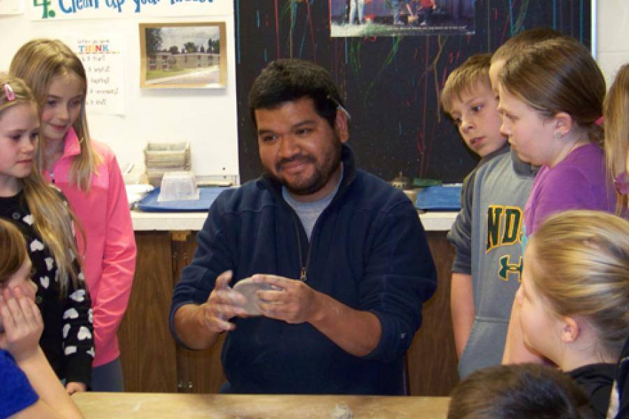 Photo of Memo demonstrating sculpture to school children