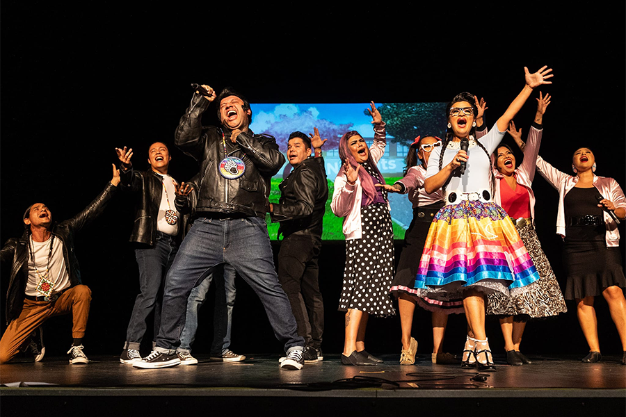 cast of ten Native American actors in full costume on stage, performing Bear Grease, an all-Indigenous reimagining of the 1978 musical Grease