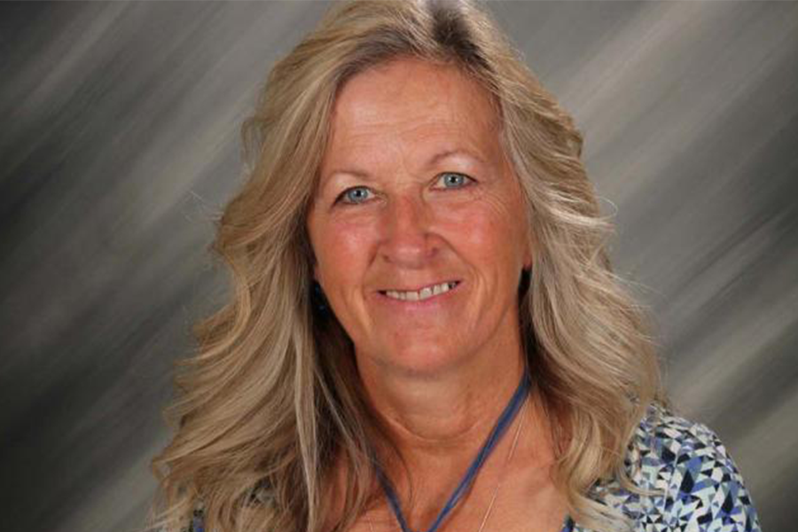Head and shoulders of Delores Halstead with long wavy blonde hair, wearing large pendant necklace