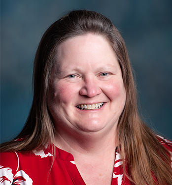 head and shoulders of caucasian Gail Schmidt with long, straight brown hair, pink cheeks and a warm toothy smile
