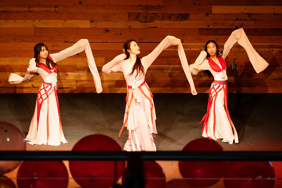 teaching artist Lexy Liu and two of her students in full dance attire performing Water Sleeve Dance