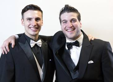 Head & shoulders of Matthew and Eric smiling, wearing black suit jackets with bowties