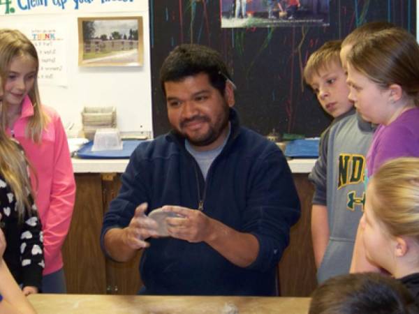 Photo of Memo demonstrating sculpture to school children