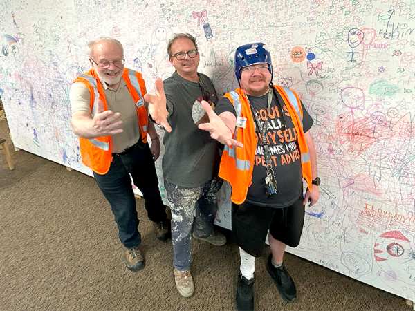 three men of varying ages and abilities, reaching out and up to the camera, wearing protective, accessible clothing