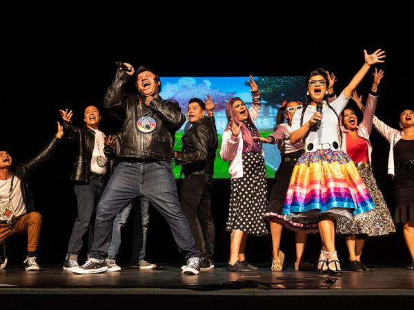 cast of ten Native American actors in full costume on stage, performing Bear Grease, an all-Indigenous reimagining of the 1978 musical Grease