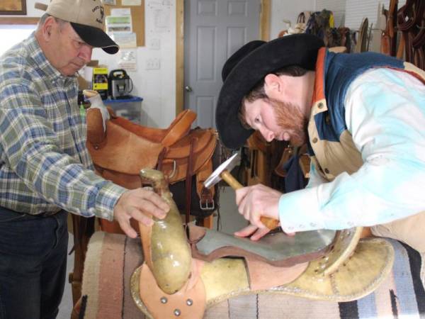 Photo of a master and apprentice working on a saddle
