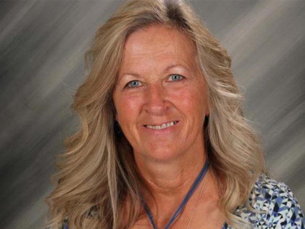 Head and shoulders of Delores Halstead with long wavy blonde hair, wearing large pendant necklace