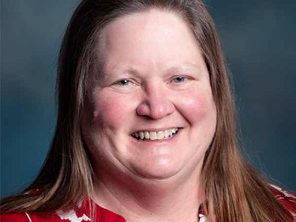 head and shoulders of caucasian Gail Schmidt with long, straight brown hair, pink cheeks and a warm toothy smile