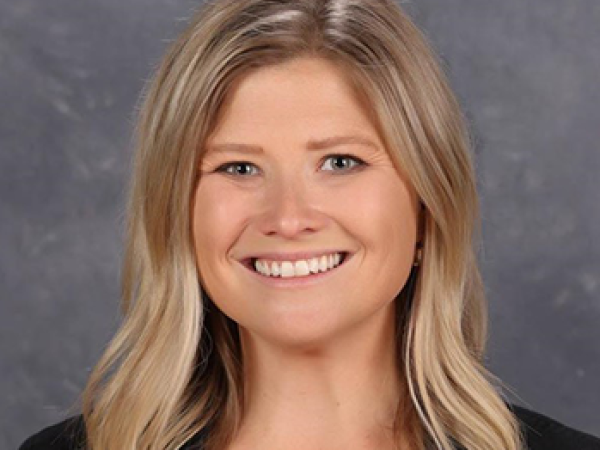 head and shoulders of caucasian Kierstin Hurtt with thick, wavy, shoulder-length blonde hair and a big toothy smile, wearing a black v-neck sweater