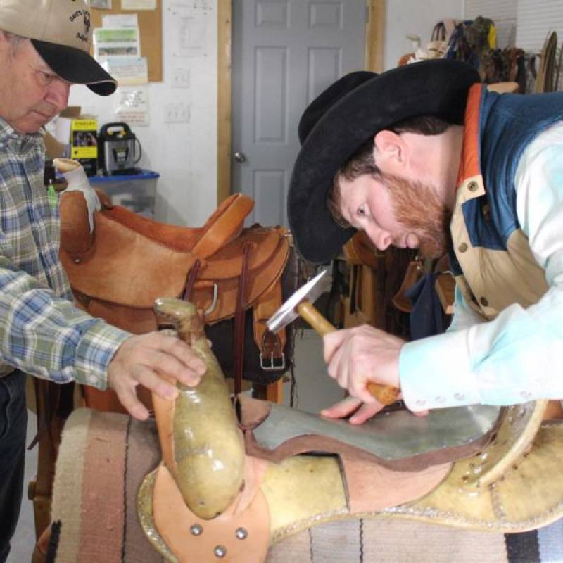 Photo of a master and apprentice working on a saddle
