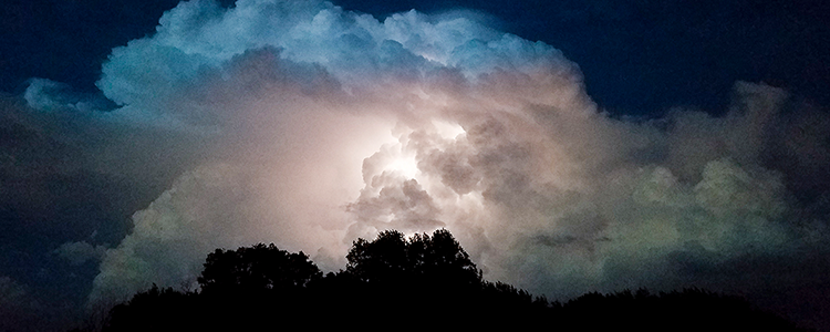 Lightning lights up storm clouds on a dark night, photo by Scott Seiler