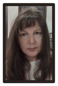 head and shoulders of caucasian artist Sherry Earl with long wavy brown hair, bangs, dark eyes and closed contrite smile