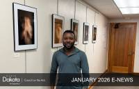 African American artist Ekow Ephrim standing in a hallway that is showcasing five of his digitally manipulated photographs