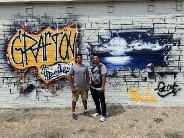Picture of two individuals in front of a mural they painted in Grafton ND