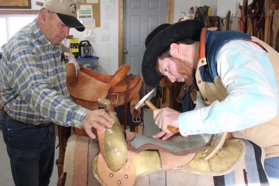 Photo of a master and apprentice working on a saddle