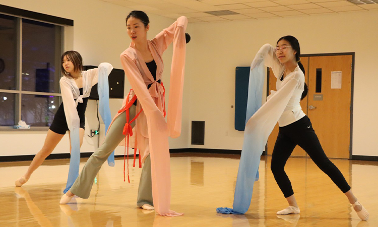 teaching artist Lexy Liu and two of her students in full dance attire performing Water Sleeve Dance