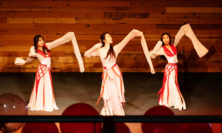 teaching artist Lexy Liu and two of her students in full dance attire performing Water Sleeve Dance