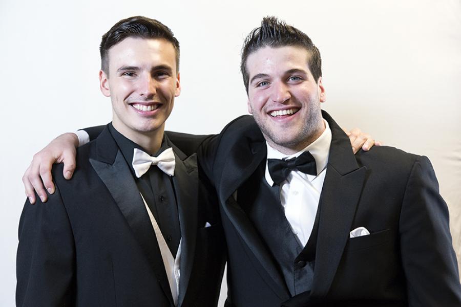 Head & shoulders of Matthew and Eric smiling, wearing black suit jackets with bowties