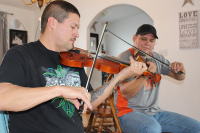 Two men playing their own fiddle together