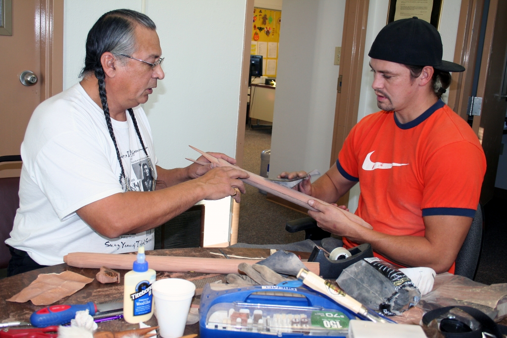 Photo of Master Mandan/Hidatsa flute maker Keith Bear of New Town, ND, teaching apprentice Cory Spotted Bear of Twin Buttes, ND flutemaking.