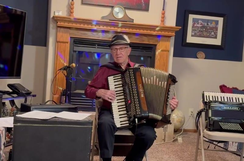 Man sits and plays accordion in living room