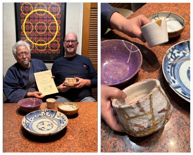 Man holding certificate beside man holding cup, several cups and bowls
