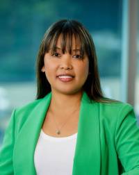 Asian America Crista McCandless with long straight, dark hair and bangs; a warm toothy smile, dark eyes; wearing a green suit jacket with a white shirt underneath