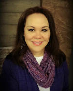 Head and shoulders of Alicia Hegland-Thorpe with long dark hair, light skin, dark eyes and toothy smile, wearing a sparkly purple scarf, white shirt and royal blue shawl