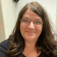 Ellen Fenner head and shoulders, fair-skinned, long curly dark hair and glasses