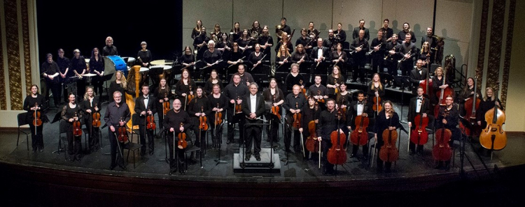 Member of Minot Symphony Orchestra standing on stage in Spring of 2022