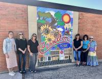6 women standing on the left and right of a mural on a wall in Casselton, ND
