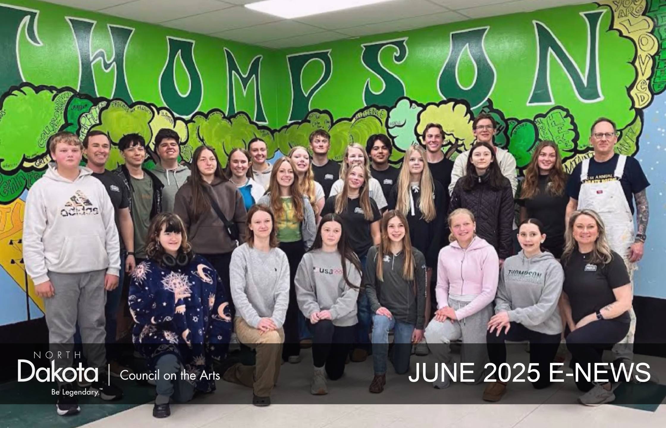 Top of NDCA's June 2025 E-newsletter showing 25 students and their teaching artist standing and kneeling in front of a 53' mural that says THOMPSON on top