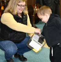 Bobbi Hepper-Olson holding donation jar for young boy
