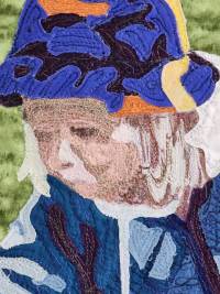 quiltwork by Jane Gaffrey, showing a stoic small child looking down and left, wearing a blue hat and blue coat with a green grassy background