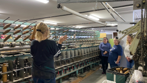 Chris Armbrust standing next to her fiber mill, explaining the equipment to onlookers