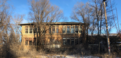 dilapidated 3-story 1916 Nome Schoolhouse with dead trees and broken windows