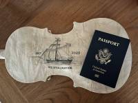 Fargo Spelemannslag 2025 “Community Build” fiddle commemorating the 200th anniversary of Norwegians crossing to America shown with a passport before it traveled to Norway itself!
