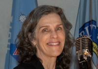 Tight headshot of Rebecca Engelman with flowing dark grey hair and a big smile