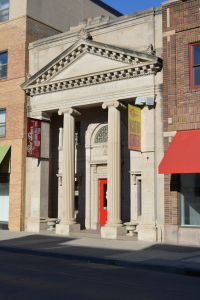 Stone building front of Red Door Art Gallery, showing 2 huge pillars with triangle on top and of course a bright red door for the entrance