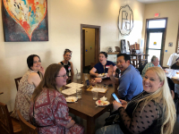 A group of people sitting at a wooden table and smiling widely at the camera