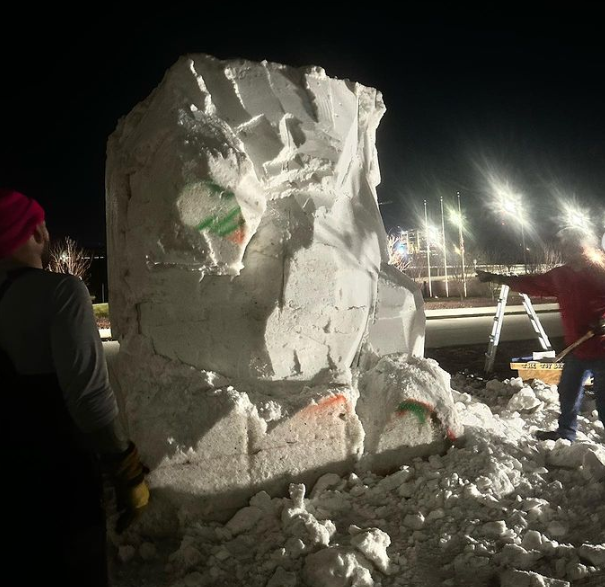 Team ND Snow Sculpting is working on a sculpture in the pitch-black night because it was too warm to carve during the day