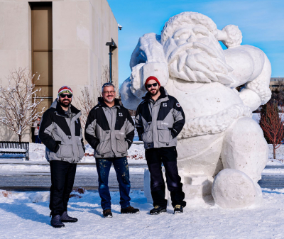 Team ND Snow Sculpting standing with a 10 foot Santa sculpture made for the 2023 Bismarck Santa Run