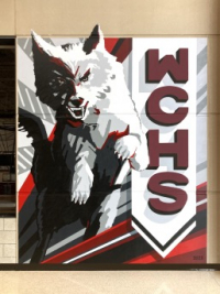 The Watford City High School Wolf mascot on the left half with the letters WCHS written vertically on the right