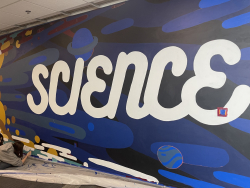 20 foot by 10 foot mural that contains abstract images, including the word SCIENCE in bright white on top of a dark background