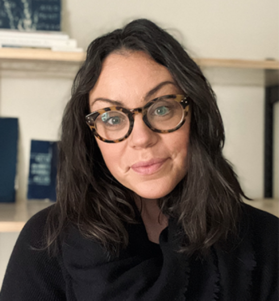 head and shoulders of Jessica Christy with long, full, straight dark hair; fair skin; dark shirt; thick, patterned rimmed round glasses; and a closed sweet smile