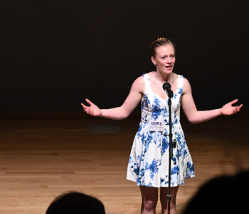 ND Poetry Out Loud web banner showing 2nd place winner Joanie McCormack, Wilton Public School, speaking on a stage